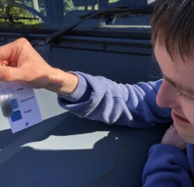 An Able2Achieve volunteer taking part in soil testing, checking the ph in the test tube